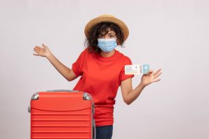 front-view-young-female-with-red-bag-mask-holding-ticket-white-background-sun-covid-pandemic-vacation-trip-tourist-color_179666-39365